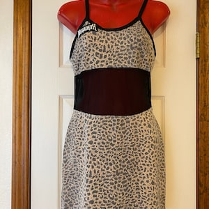May include: A sleeveless mini dress with a leopard print pattern. The dress has a black mesh panel and the word "Megadeth" is embroidered on the front.