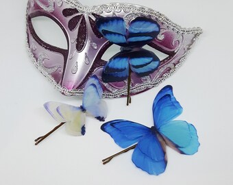 May include: Four silk butterfly hair clips, two blue and two white, with a purple and silver masquerade mask in the background. The text "Cudddollzz Silk Butterfly Accessories" is at the top of the image.