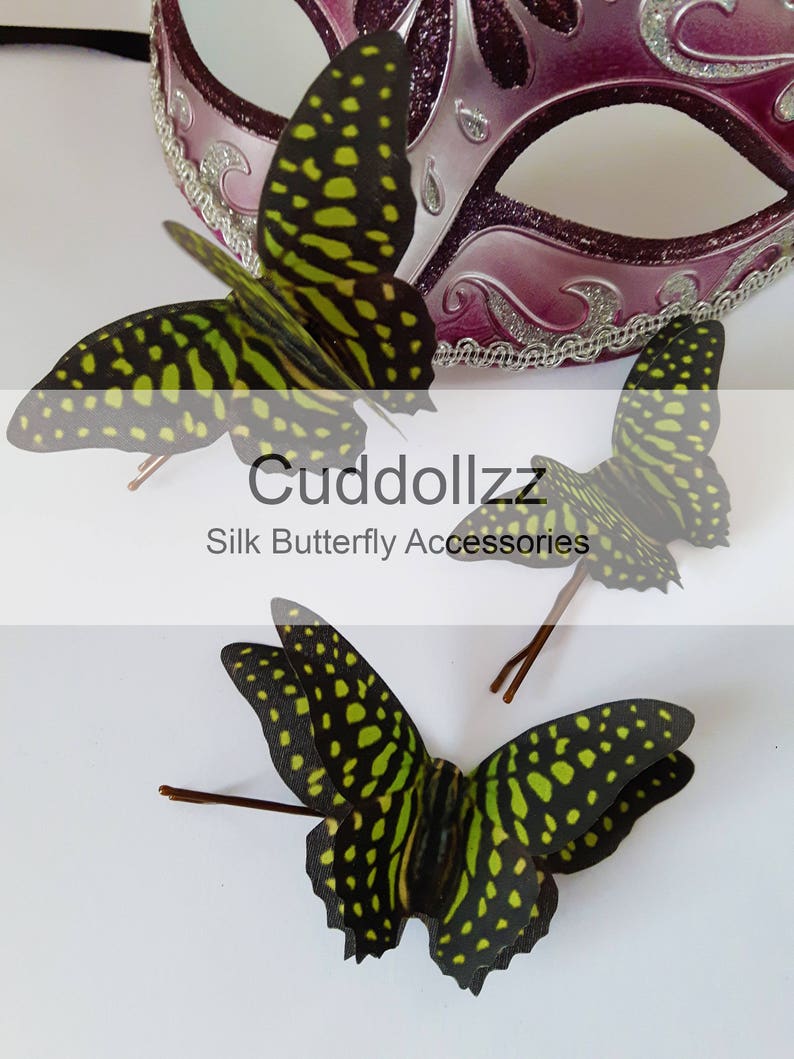May include: Three green and black silk butterfly hair clips with brown wire stems. The butterflies have a spotted pattern. The text "Cudddollzz Silk Butterfly Accessories" is visible below the butterflies.