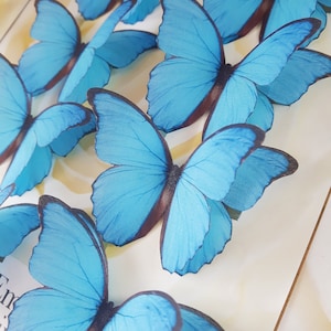 May include: A collection of blue butterfly decorations. The butterflies are made of a delicate material and have a realistic appearance.