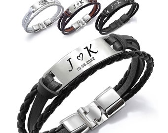 May include: Black leather bracelet with a silver metal plate engraved with the letters "J♥K" and the date "10.08.2022". The bracelet has a braided leather design and a silver metal clasp.
