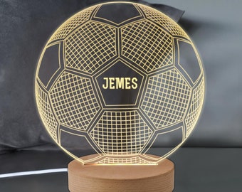 May include: A wooden base with a 3D printed soccer ball night light. The soccer ball is outlined in gold and has the name "Jemes" printed on it.