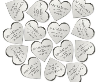 Op de afbeelding: Zilveren hartvormige bruiloftsgeschenken met de tekst "Mark & Susan" en de datum "19.08.22" gegraveerd op elk.