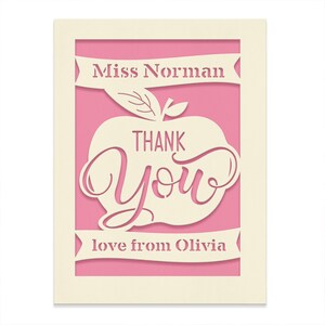 May include: A pink card with a white apple cut out. The apple has the words "Thank You" inside. The card also has the text "Miss Norman" and "love from Olivia" on it.