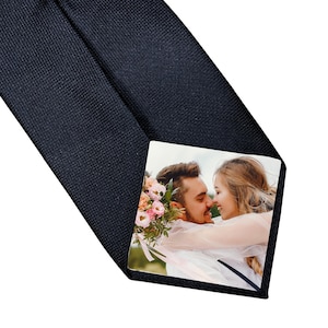 May include: Navy blue tie featuring a personalized photo print. The print shows a couple embracing, with a bouquet of flowers. The tie is made of a textured fabric, suitable for formal events.