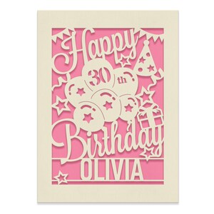 May include: A pink card with a white cut-out design of the words "Happy 30th Birthday Olivia" with balloons, stars, and a party hat.