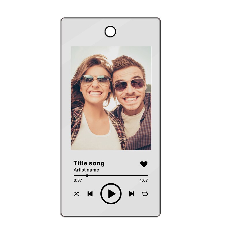 Pu&ograve; includere: Un lettore musicale digitale bianco con una foto di una coppia che indossa occhiali da sole e sorride. Il lettore ha un pulsante di riproduzione, un'icona a forma di cuore e il testo "Title song" e "Artist name".