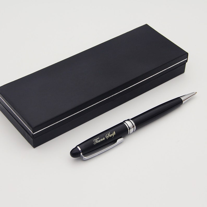 May include: A black pen with a silver trim and the name "Tiana Swift" engraved on it. The pen is in a black box with a silver trim.