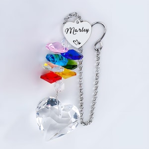 Puede incluir: Un atrapasoles de cristal en forma de coraz&oacute;n con un arco&iacute;ris de cristales de colores y una cadena plateada. El atrapasoles tiene una etiqueta en forma de coraz&oacute;n con el nombre "Marley" y un s&iacute;mbolo de coraz&oacute;n.