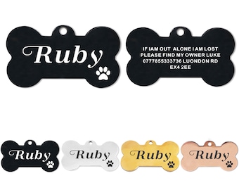 May include: A set of four dog tags in different colors: black, silver, gold, and rose gold. Each tag is shaped like a bone and has the name "Ruby" engraved on it. The black tag also includes contact information for the owner.