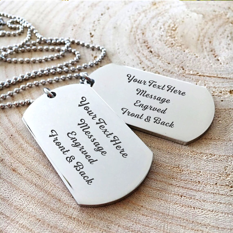 K&ouml;nnte beinhalten: Zwei silberne Hundemarken an einer silbernen Kette. Die Hundemarken sind mit dem Text "Your Text Here Message Engraved Front & Back" graviert.