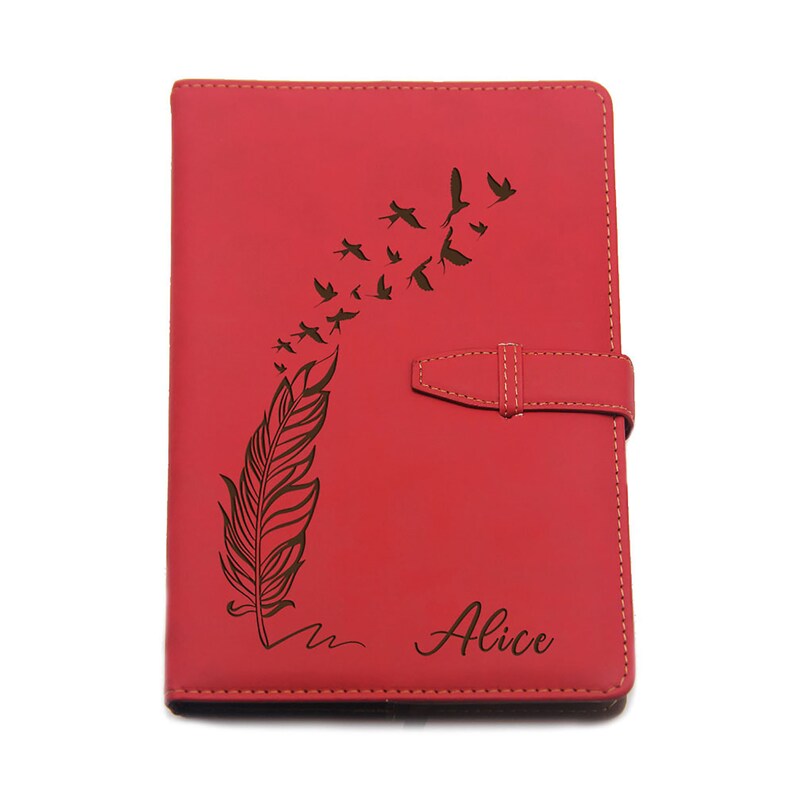 Puede incluir: Diario de cuero rojo con un dise&ntilde;o grabado con l&aacute;ser de una pluma y p&aacute;jaros en vuelo. El diario tiene un cierre de solapa y el nombre "Alice" est&aacute; inscrito en la portada. Un accesorio elegante para escribir y tomar notas.