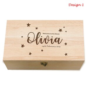 May include: A light wood keepsake box with a hinged lid and a brass latch. The top of the box is engraved with the text "Welcome to the World Olivia 14th February 2019" and a scattering of stars.