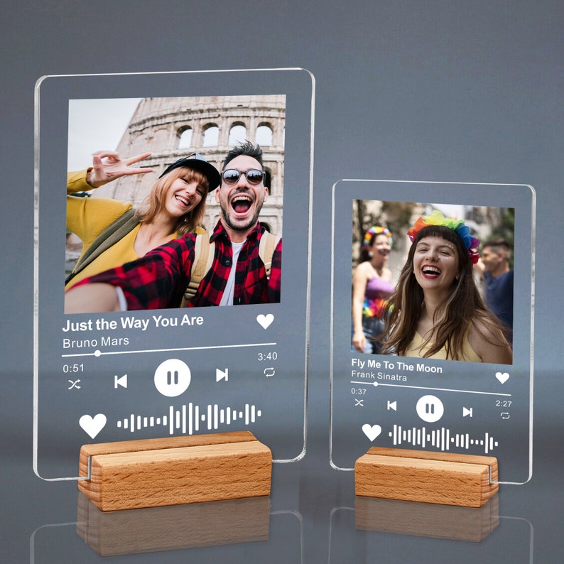 May include: Two clear acrylic photo displays with wooden bases. Each display features a photo and a music player interface. One shows "Just the Way You Are" by Bruno Mars, the other "Fly Me To The Moon" by Frank Sinatra. A unique gift idea.