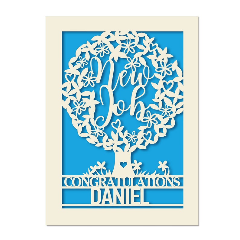 May include: A white card with a blue background. The card features a white paper cut-out design of a tree with the words "New Job" inside the tree. The text "Congratulations Daniel" is below the tree.