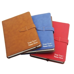 May include: Three leather-bound journals in brown, blue, and red with a strap closure. Each journal has the text "Your Text/Name Here" embossed in white.