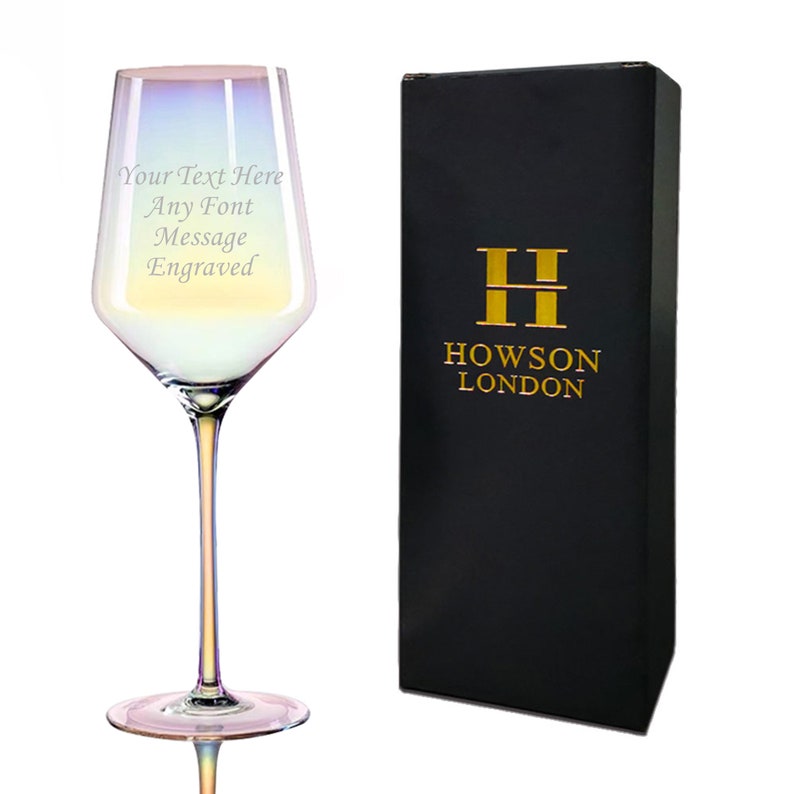 May include: A clear iridescent wine glass with a gold inscription that reads "Your Text Here Any Font Message Engraved". The glass is in a black box with a gold logo that reads "Howson London".