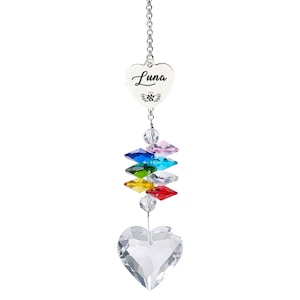 Puede incluir: Un atrapasoles de cristal en forma de coraz&oacute;n con el nombre "Luna" grabado en un dije en forma de coraz&oacute;n. El atrapasoles presenta un arco&iacute;ris de cristales de colores y un gran cristal en forma de coraz&oacute;n en la parte inferior, suspendido por una cadena plateada.