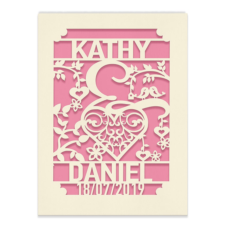 May include: A pink and white wedding invitation with a cut-out design featuring a heart, birds, and the names "Kathy & Daniel" with the date "18/07/2019".