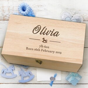 May include: A wooden keepsake box with a light wood finish. The box is engraved with the name Olivia, a rocking horse, and the text "7lb 6oz Born 16th February 2019".