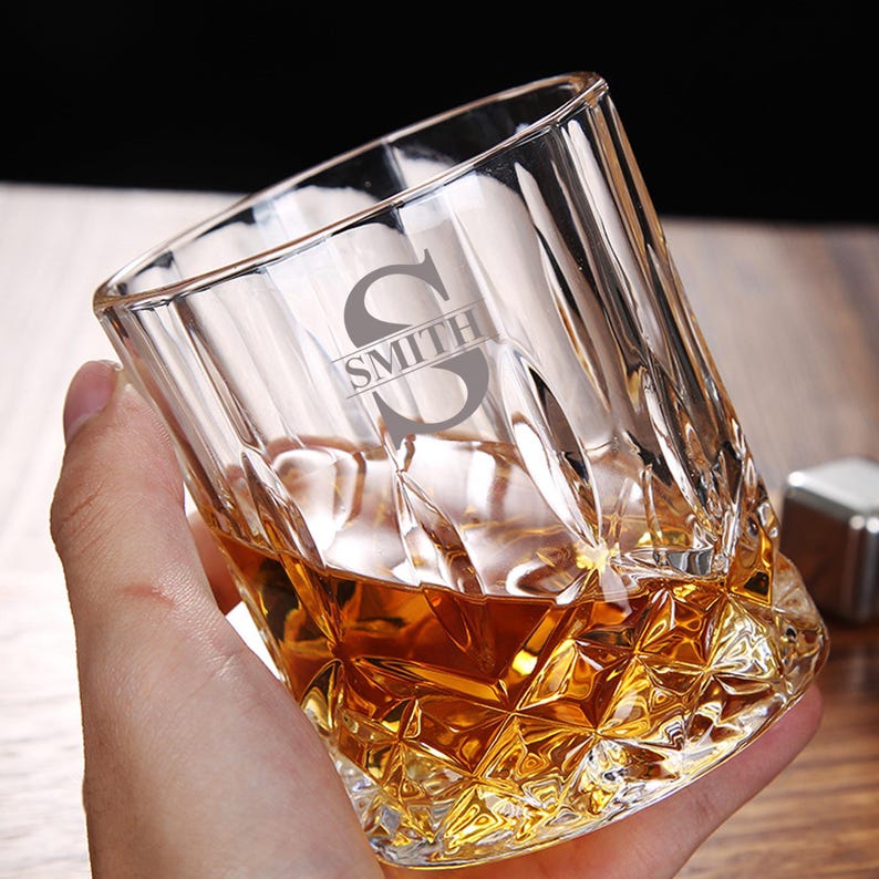 May include: A clear glass whiskey tumbler with a cut-glass design. The glass has the initial "S" and the name "SMITH" engraved on the side.