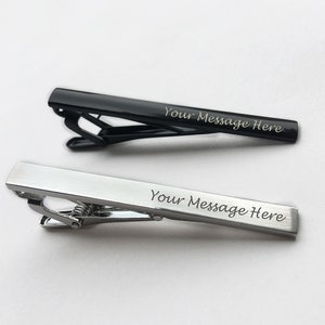 May include: Two tie clips, one black and one silver, with the text "Your Message Here" engraved on each.
