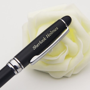 May include: A black pen with a silver clip and a gold inscription that reads "Sherlock Holmes".