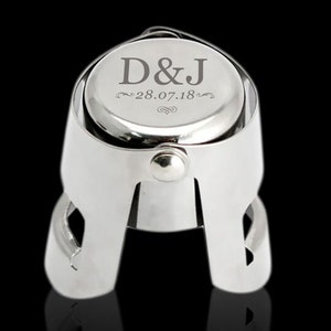 May include: Silver champagne bottle stopper with a round top engraved with the initials "D&J" and the date "28.07.18".