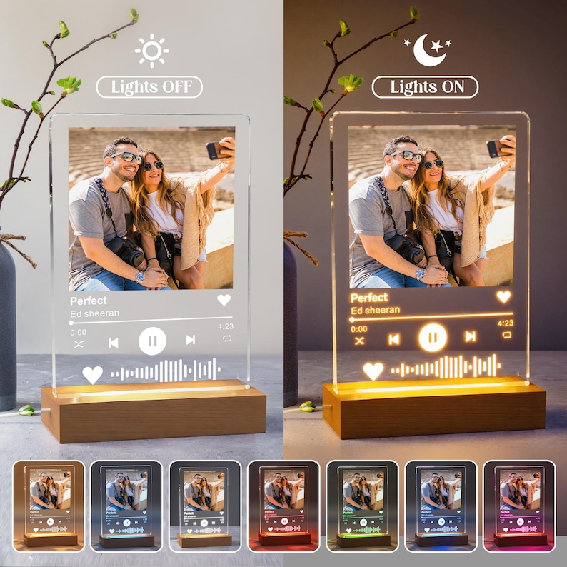 May include: A clear acrylic photo display with a wooden base. The display features a photo of a couple and a music player interface with the song title "Perfect" by Ed Sheeran. The base emits a warm glow when the lights are on, and the display has multiple color options.