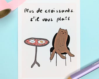 May include: A whimsical illustration features a brown cat seated on a chair, with a small table holding a coffee cup and a croissant. The text "Plus de croissants, s'il vous plaît" is written above the cat. A purple pencil and pink tape are in the image.