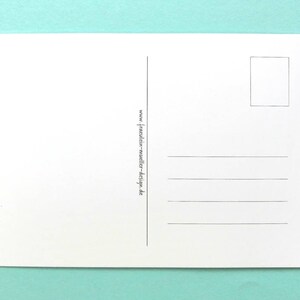 May include: A blank white postcard with a rectangular stamp box and horizontal lines for writing. The text "www.fraulein-mueller-design.de" is printed vertically along the left side. The postcard is on a light teal background.