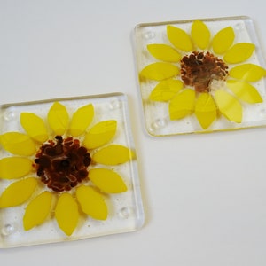 Peut inclure: Deux sous-verres en verre avec un motif de tournesol. Les tournesols sont jaunes avec des centres bruns et sont plac&eacute;s sur un fond de verre transparent.