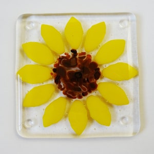Peut inclure: Un dessous de verre en verre avec un motif de tournesol. Le tournesol est jaune avec un centre brun. Le dessous de verre est en verre transparent.