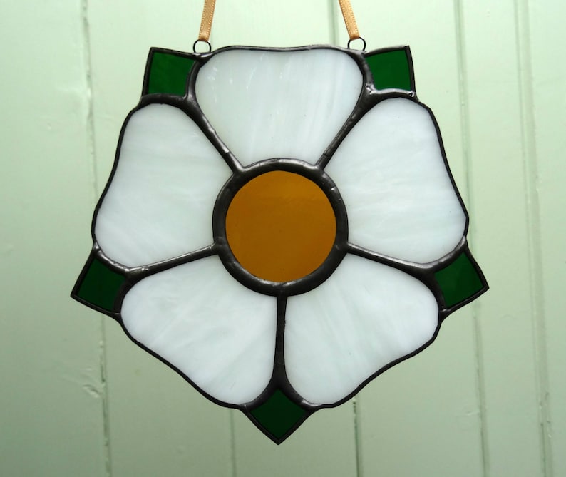A stained glass panel featuring a white rose with a yellow centre. The rose is surrounded by a border of green leaves. It is a Yorkshire Rose. Also available is the red version for Lancashire. naomisglass.co.uk