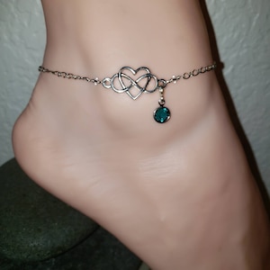 Può includere: Cavigliera color argento con un design a cuore infinito e una gemma pendente color verde acqua. La delicata catena è collegata al cuore infinito e alla gemma. Un elegante gioiello.