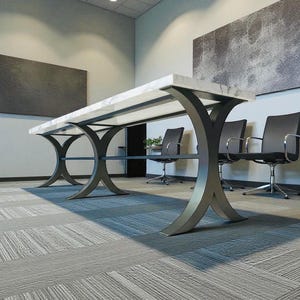 May include: A large, modern conference table with a white marble top and dark gray, curved metal legs. The table is in a well-lit room with black chairs and abstract art on the walls. The room has a gray patterned carpet.