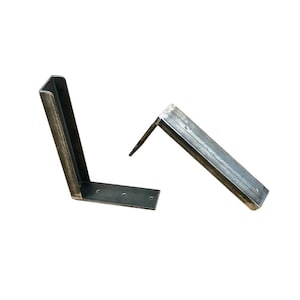 May include: Two metal shelf brackets, each with a 90-degree angle and multiple holes for mounting. The brackets are made of unfinished steel and have a rustic look.