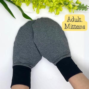 May include: A pair of grey adult mittens with black cuffs. The text "Adult Mittens" is written in yellow on a white background.