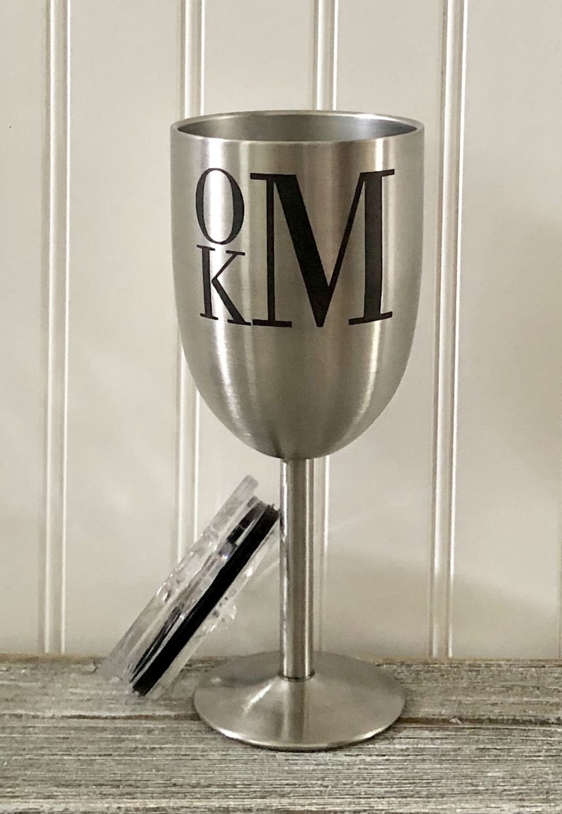 May include: A stainless steel wine tumbler with a black lid and the initials "OKM" printed on the side.