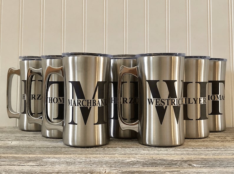 Puede incluir: Ocho tazas de viaje de acero inoxidable con iniciales y nombres personalizados. Las tazas tienen un acabado plateado y letras negras.