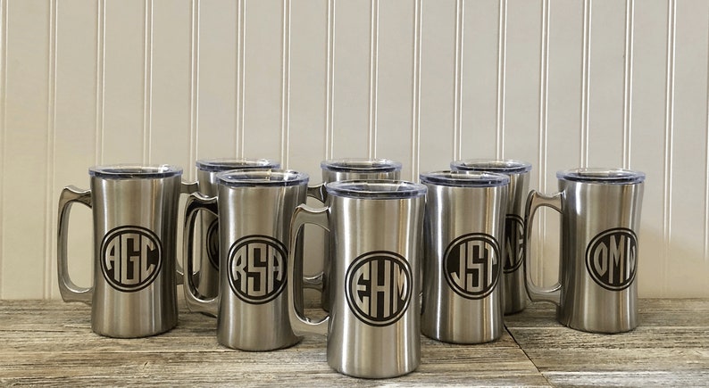 Puede incluir: Ocho tazas de viaje de acero inoxidable con tapas. Cada taza tiene un monograma diferente grabado en la parte delantera. Los monogramas est&aacute;n en un c&iacute;rculo con un contorno negro.