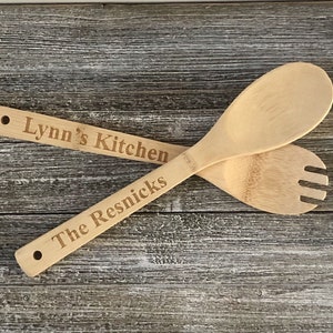 May include: Two wooden kitchen utensils, a spoon and a fork, with the text "Lynn's Kitchen" and "The Resnicks" engraved on them.