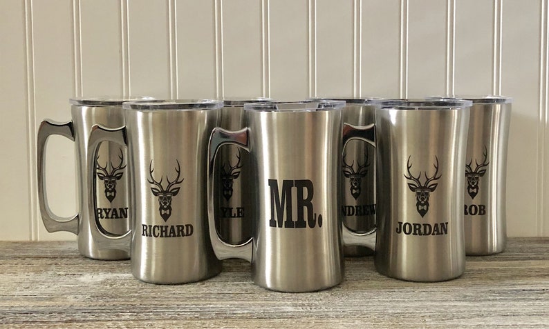 Puede incluir: Seis tazas de viaje de acero inoxidable con asas y tapas negras. Cada taza tiene un dise&ntilde;o diferente, incluyendo un ciervo con cuernos, una pajarita y un nombre. Los nombres en las tazas son Ryan, Richard, Kyle, Mr., Andrew y Jordan.