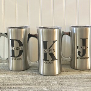 Puede incluir: Tres tazas de viaje de acero inoxidable con tapas. Las tazas est&aacute;n personalizadas con los nombres Derek, Kevin y Justin, junto con sus roles en una fiesta de boda: padrino, novio y padrino.