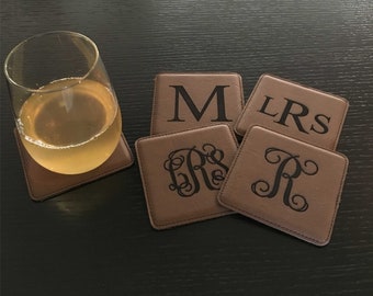 May include: Set of four brown leather coasters with monogrammed initials. The initials are "M", "LR", "RS", and "R".
