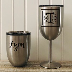 May include: Two stainless steel tumblers, one with the name "Lynn" and the other with the letter "T" in a decorative font inside a square.