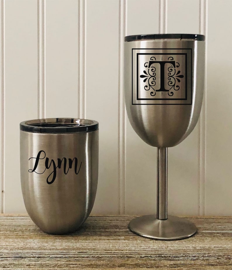 May include: Two stainless steel tumblers, one with the name "Lynn" and the other with the letter "T" in a decorative font inside a square.