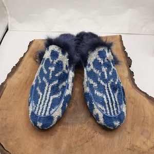 May include: A pair of blue and white patterned slippers with a faux fur lining. The slippers are on a wooden surface.