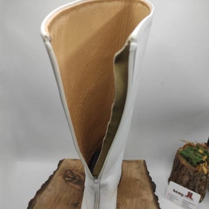 Puede incluir: Botas blancas de cuero de ca&ntilde;a alta con cremallera en la parte posterior. Las botas est&aacute;n forradas con un tejido marr&oacute;n.