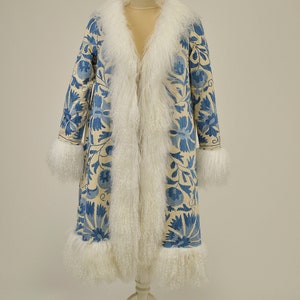 May include: A long off white fur-trimmed coat with a blue and white floral pattern. The coat is displayed on a white mannequin.